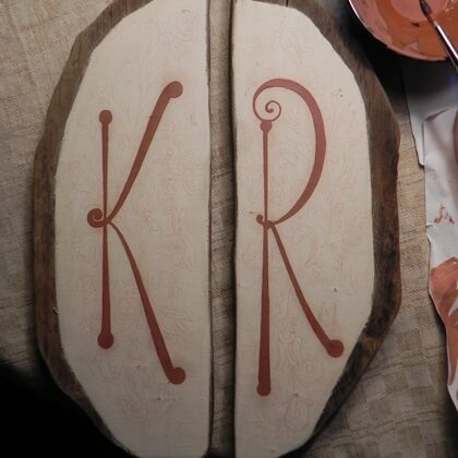 The drawing transferred to the board and the letters are ready for gilding on red clay